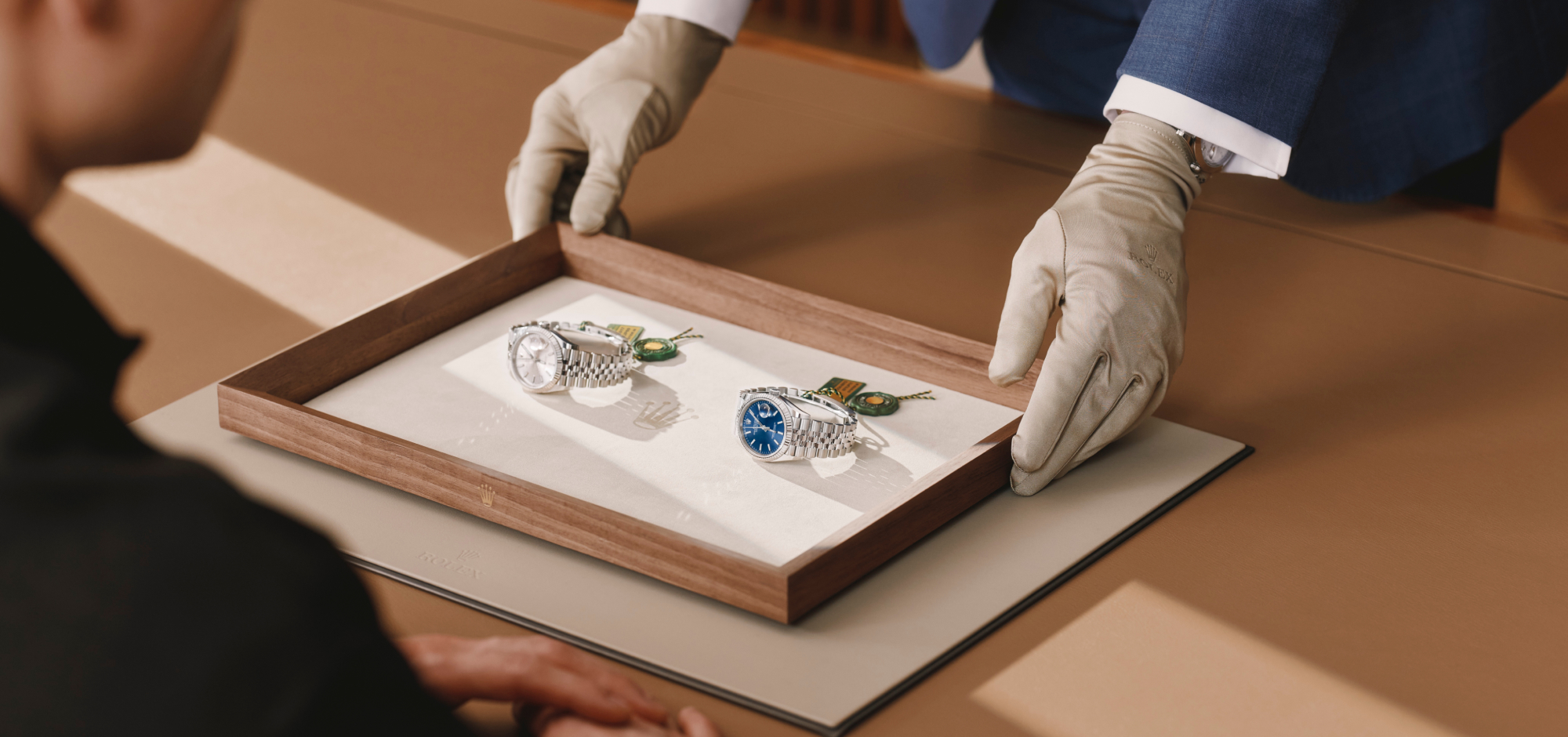 Zwei Rolex Datejust auf Holztablett — Übergabe an den Fachhändler mit weißen Handschuhen
