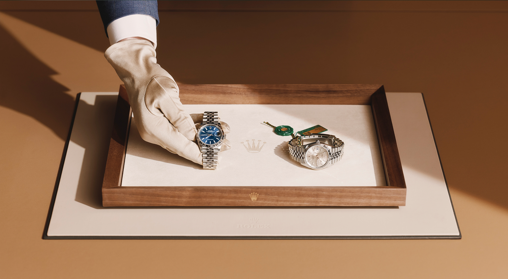 Rolex Fachhändler — autorisierte Übergabe zweier Datejust auf Holztablett mit grünen Siegeln